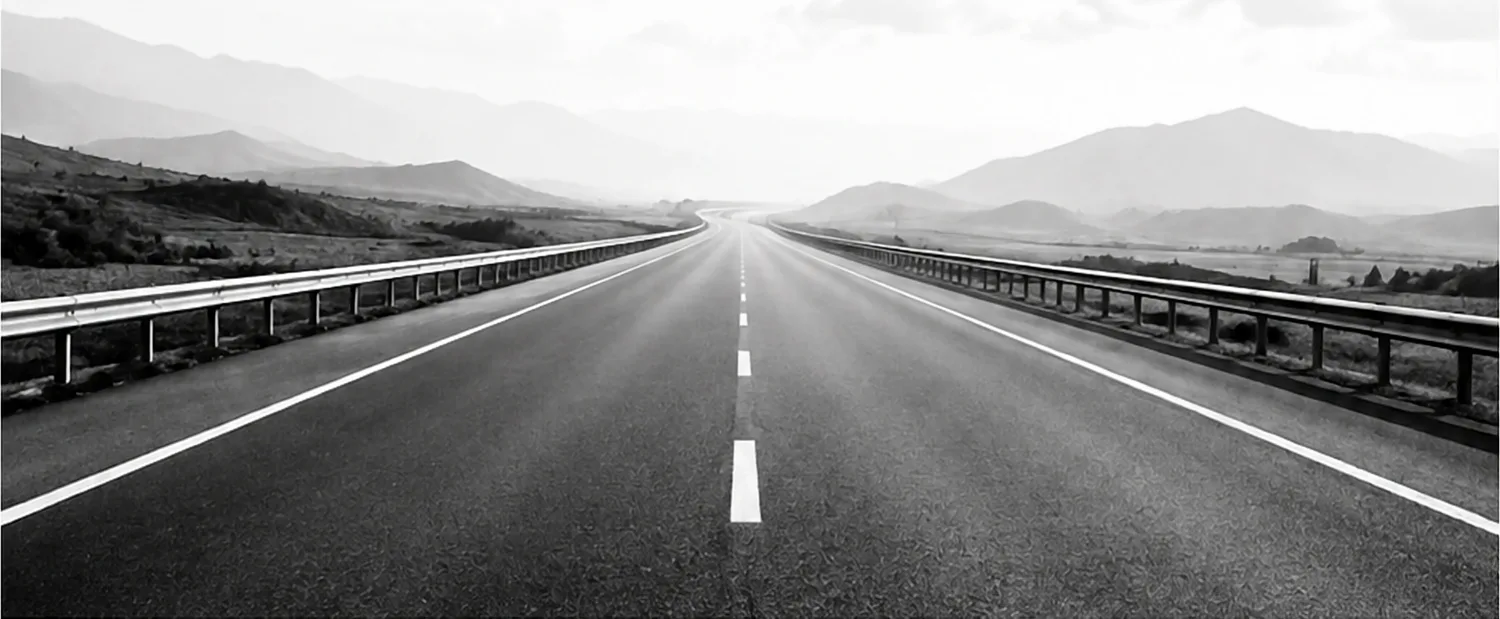 An empty highway running straight towards the mountains